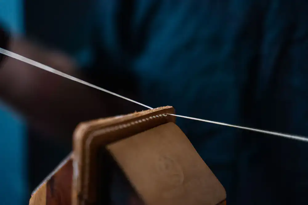 A bookbinder's hands carefully stitching a bespoke leather journal with thick linen thread