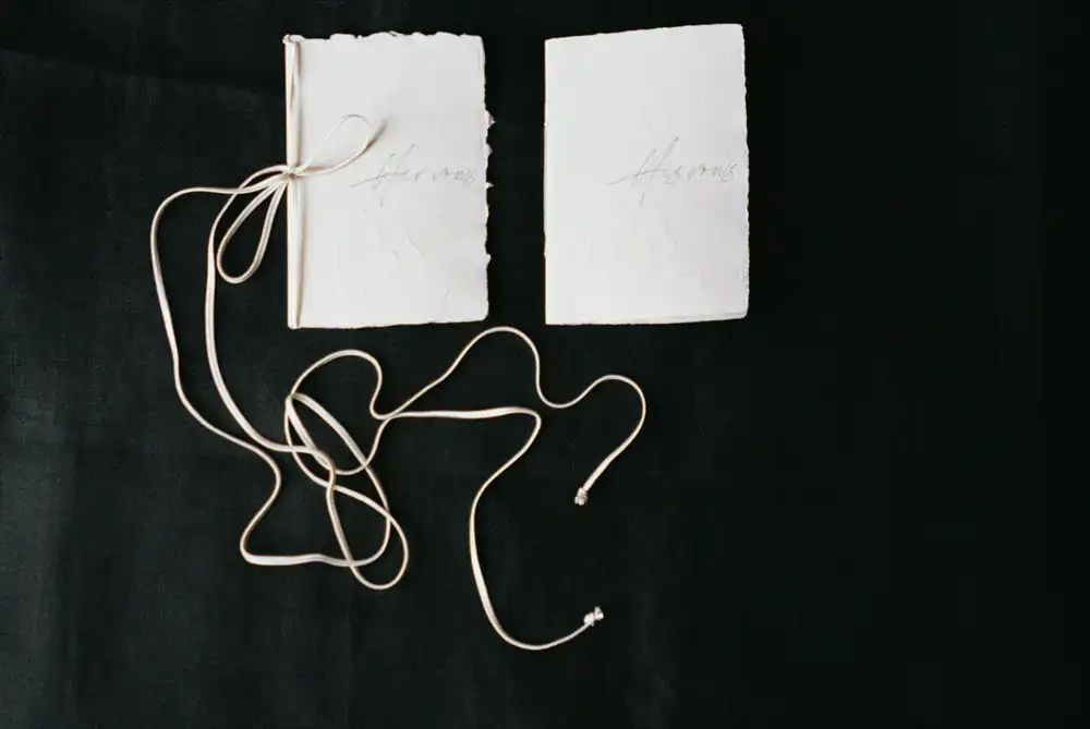 A custom hand-bound journal with a dark leather cover resting on a wooden desk