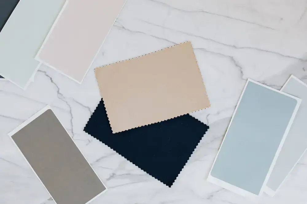 Various marble paper samples, leather swatches, and colored binding threads laid out on a viewing table