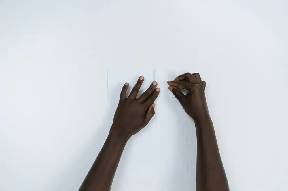 Student hands folding textured paper with a traditional bone folder